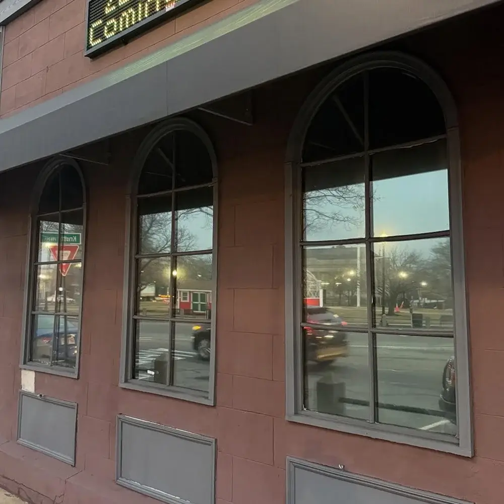 Street-facing commercial building with three arched windows, each covered in dark privacy tint.