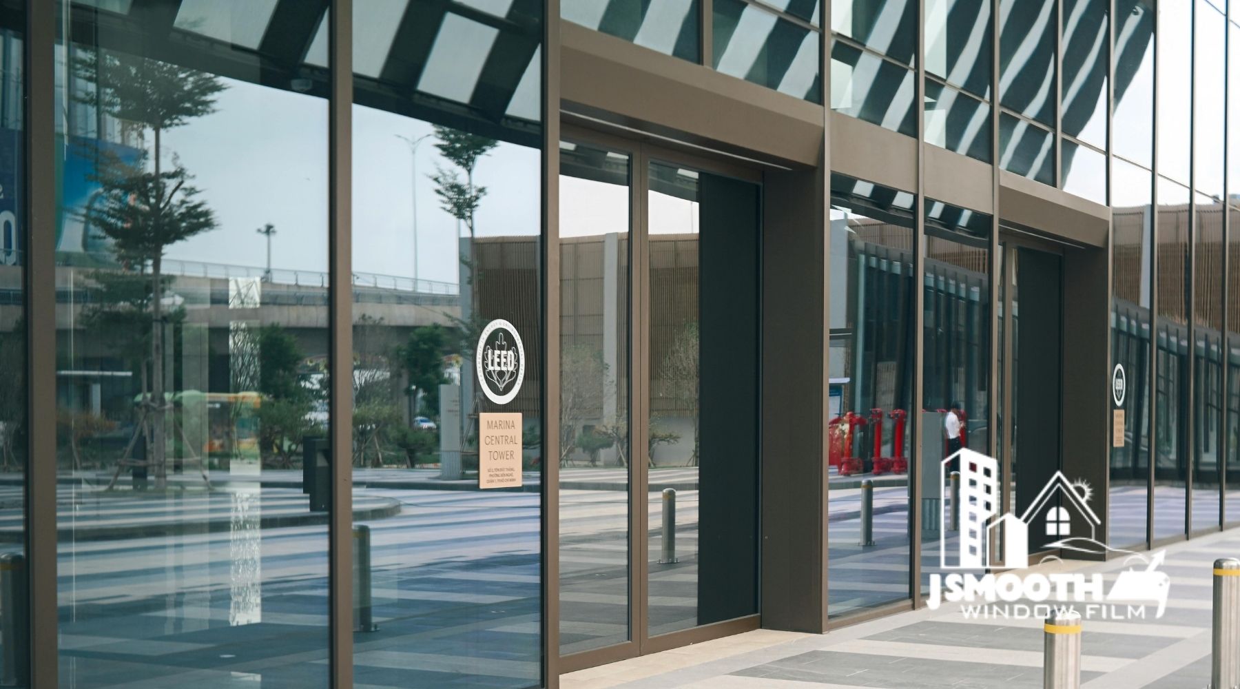 Commercial window tinting on a modern office storefront with large glass windows and J Smooth Window Film branding.
