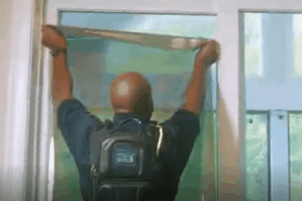 Professional installer applying window film to a large glass window for improved privacy, glare control, and solar protection.